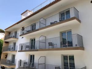 un edificio blanco con balcones, mesas y sillas en Malva Hostel en L'Estartit