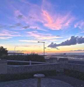 een zonsondergang boven een strand met een straatlicht en een straatlicht bij Villa lumineuse en front de mer - Gold Beach in Asnelles