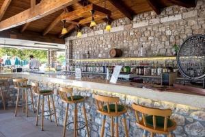 un bar con taburetes de madera y una pared de piedra en Aegean View Aqua Resort en Psalidi