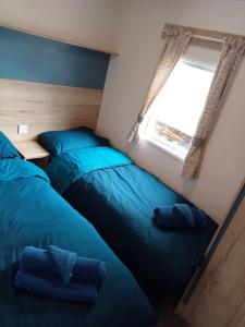 1 dormitorio con 2 camas y ventana en New 2 bed holiday home with decking in Rockley Park Dorset near the sea, en Lytchett Minster