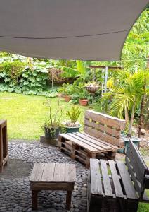 2 bancs en bois et une table sous un parasol dans l'établissement Rava Lodge, à Punaauia