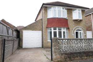 a house with a white garage door and a fence at A stylish four bedroom house in wollaton in Nottingham