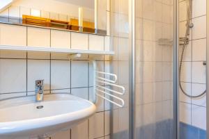 La salle de bains est pourvue d'un lavabo et d'une douche. dans l'établissement Haus Suedwind, à Hooksiel