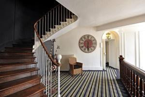 un couloir avec des escaliers et une horloge sur le mur dans l'établissement LOGIS Hôtel de Bourgogne - Mâcon, à Mâcon