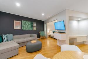 uma sala de estar com um sofá e uma televisão em Salt&Pepper Sanctuary - Plunge Pool Resort Apartment by uHoliday - 2BR, 1BR and Studio Hotel Room configurations available em Kingscliff