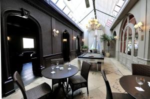 un restaurant avec deux tables et chaises et un lustre dans l'établissement LOGIS Hôtel de Bourgogne - Mâcon, à Mâcon