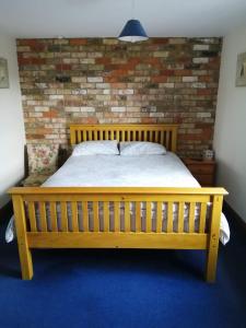 a wooden bed in a room with a brick wall at The Old School in Donington on Bain