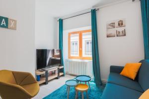 a living room with a blue couch and a tv at La Halte de Saint-Pierre in Clermont-Ferrand