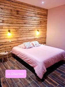 - une chambre avec un lit et un mur en bois dans l'établissement Gite La Charme avec spa, 