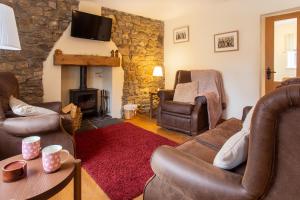 a living room with leather furniture and a stone fireplace at Lovely 3-Bed Cottage in the quiet hamlet of Horeb in Brondini