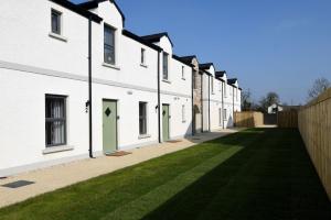 een rij witte huizen met groene deuren bij Homestead Hillsborough Guest Rooms in Hillsborough