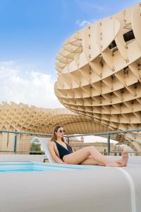 una mujer sentada en el borde de una piscina en un barco en Welldone Metropol, en Sevilla