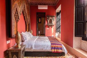 a bedroom with red walls and a bed with a mirror at Palais El Roucar in Marrakesh