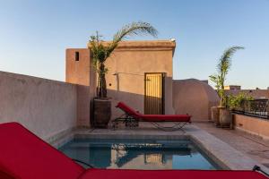 a swimming pool with a red chair next to a building at Palais El Roucar in Marrakesh