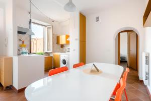 a white kitchen with a white table and orange chairs at Giulia Apartment in Trastevere in Rome