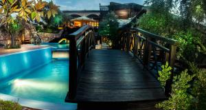a bridge over a pool with a house in the background at Kallisti Hotel in Potos