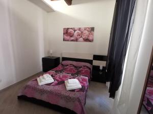 a bedroom with a bed with pink sheets and two towels at Casa 700 in Civitavecchia