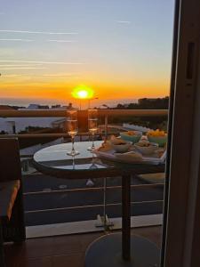 einen Tisch mit Essen und Weingläsern auf einem Balkon mit Blick auf den Sonnenuntergang in der Unterkunft Amazing Lodge by the Ocean - Fully equipped! in Ericeira