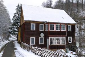 a wooden house with snow on the roof at Haus am Wald Zorge 16+ Gäste in Walkenried