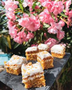 a group of carrot cake bars with frosting and pink flowers at El Nido de Alaro - Turismo de Interior in Alaró