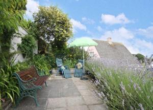 a patio with two benches and an umbrella at Spacious Detached House with Parking & Views in Fowey