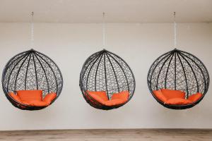 tres jaulas de aves colgantes con asientos naranjas en una pared en Vesiroos Apartment, en Pärnu