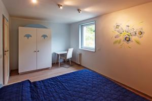 a bedroom with a blue bed and a desk with a window at La Marmote Albergo Diffuso di Paluzza Piles in Paluzza