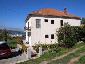 a white house with a red car parked next to it at Apartment Pasman 1 in Pašman +13 photos