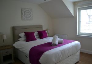 基林的住宿－Inverfinn，一间卧室配有一张大床,提供紫色和白色枕头