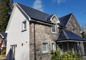 a stone house with a black roof at Capercaillie in Killin