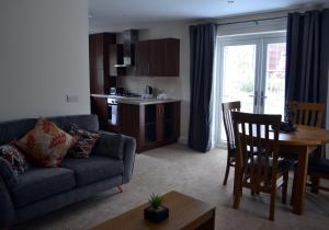 ein Wohnzimmer mit einem Sofa und einem Tisch sowie eine Küche in der Unterkunft Capercaillie in Killin