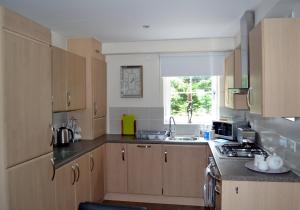 a kitchen with wooden cabinets and a sink and a window at Álainn Eve in Killin