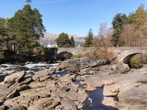 een stenen brug over een rivier met rotsen bij Álainn Eve in Killin