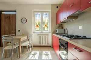 a kitchen with red cabinets and a table with chairs at Apartment Maya - Tremezzina in Tremezzo
