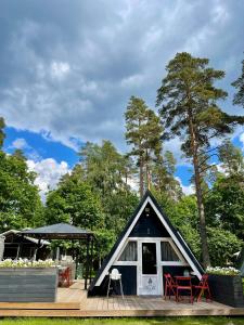 mały domek z tarasem i czerwonymi krzesłami w obiekcie Camping Milk w mieście Usmenieki