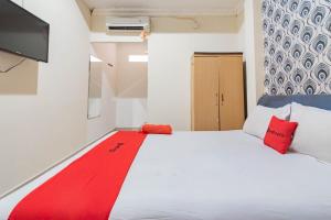 a bedroom with a large white bed with red pillows at RedDoorz near Pasar Klandasan Balikpapan in Balikpapan