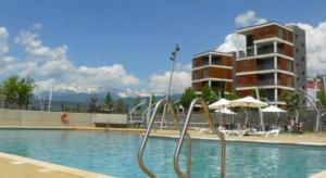 a swimming pool with a hotel in the background at Margas Golf Apartment in Sabiñánigo +17 photos