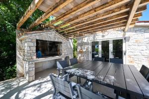 a patio with a table and a stone fireplace at Vila Radini in Brtonigla