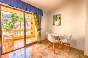 ein Esszimmer mit einem Tisch und Stühlen sowie einem Balkon in der Unterkunft Estudio castle harbour 403 los Cristianos in Los Cristianos
