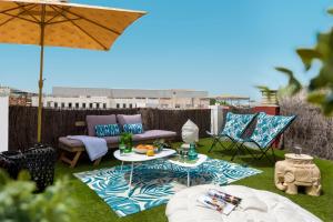 patio con tavolo, sedie e ombrellone di MonKeys Apartments Luxury Penthouse Cathedral & Terrace a Siviglia