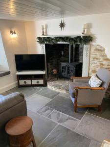 a living room with a television and a fireplace at Beautiful 1 bed thatched cottage in Dolton