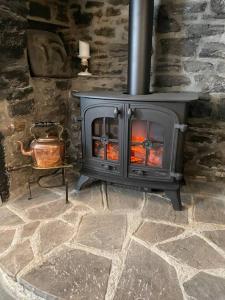 a stone fireplace with a stove in a room at Beautiful 1 bed thatched cottage in Dolton