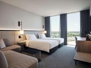 ScoresbyにあるHyatt Place Melbourne Caribbean Parkのベッド2台とソファが備わるホテルルームです。