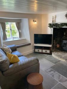 a living room with a couch and a television at Beautiful 1 bed thatched cottage in Dolton