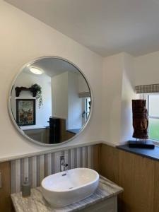 y baño con lavabo blanco y espejo. en Beautiful 1 bed thatched cottage en Dolton