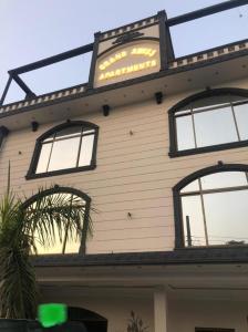 ein Gebäude mit drei Fenstern und einem Schild darauf in der Unterkunft Grand Swiss Hotel&Apartment Lahore in Lahore