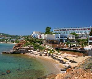 a beach with umbrellas and chairs and the ocean at Erytha Hotel & Resort Chios in Karfas