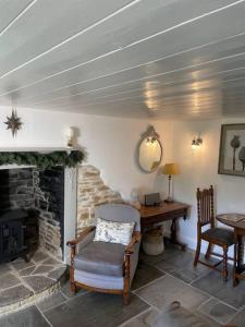 Camera con camino, sedia e scrivania. di Beautiful 1 bed thatched cottage a Dolton