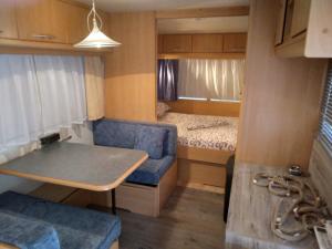 Caravana pequeña con sofá azul y cama en Camping Goldfish, en Sozopol