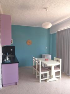 a kitchen with a white table and a blue wall at THE BONGOS - Socially Conscious Rooms, Part of the room rate goes to charity in Maleme